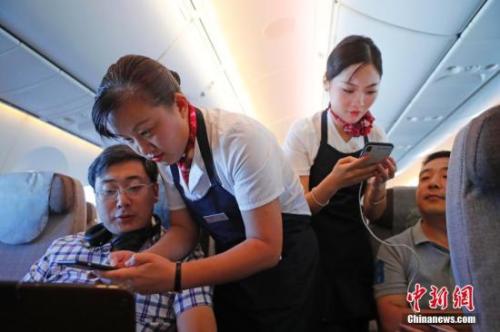 資料圖：乘務(wù)員們在客艙內(nèi)為旅客調(diào)試機上上網(wǎng)功能。<a target='_blank' ><p  align=